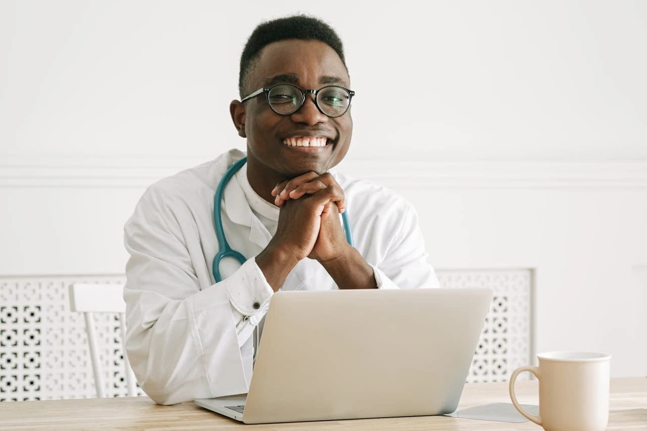 Image of a smiling doctor posing with their laptop, symbolising someone who did things right